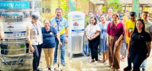 Eine Gruppe von Menschen steht um zwei große Edelstahltanks für Trinkwasser.
